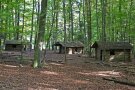 Hölzerne Blockhütten stehen locker verteilt im Wald