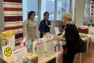 3 Personen stehen um einen Tisch