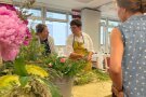 Personen stehen um Blumengestecke