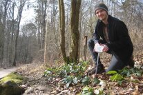 Junger Mann im Wald mit einen Schild zur Benennung von Pflanzen