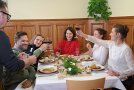 Menschen sitzen an Tisch und stoßen mit Wein an.